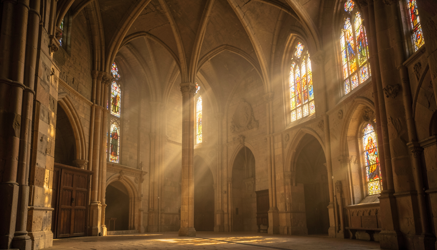 A grand stone abbey interior with soaring arches and stained-glass windows, bathed in warm golden-hour light filtering through coloured glass.