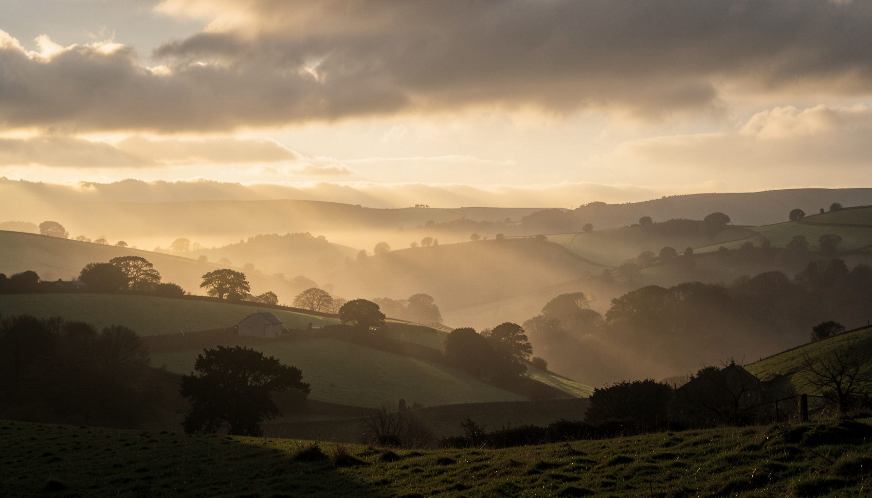 Misty dawn over rolling Yorkshire countryside, soft golden light breaking through low cloud, tranquil and sombre mood